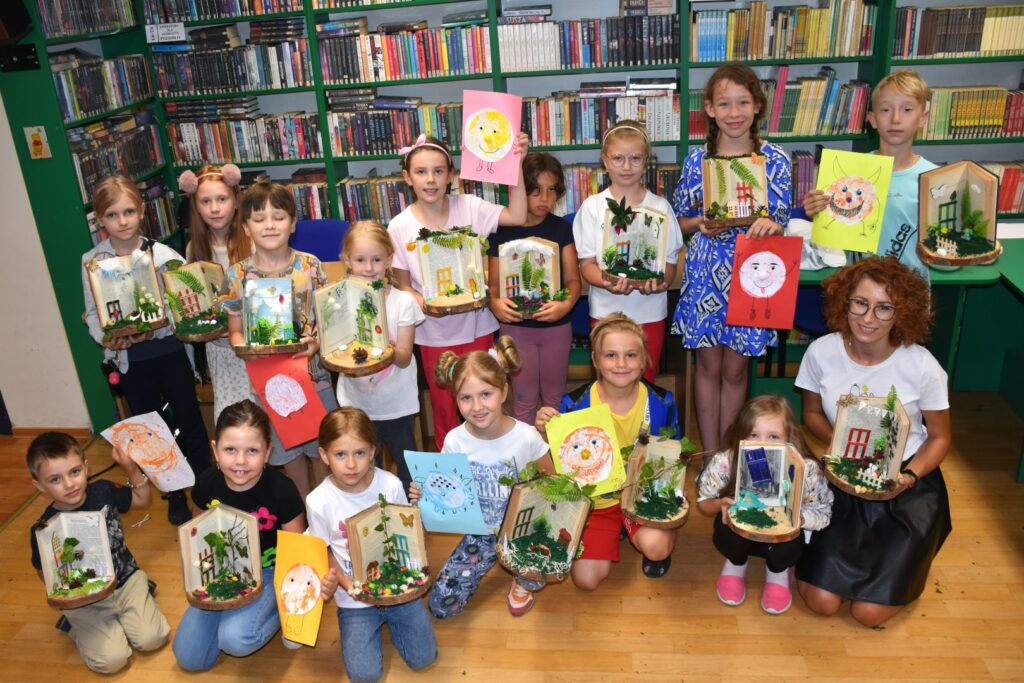 Zdjęcie grupowe - dzieci prezentujące ksiązki artystyczne, które stworzyły w trakcie wakacyjnych warsztatów w bibliotece