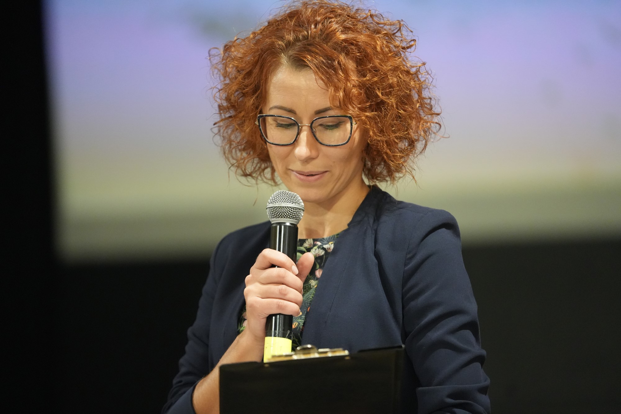 Spotkanie górskie klimaty - dyrektor biblioteki z mikrofonem w ręku zapowiada spotkanie