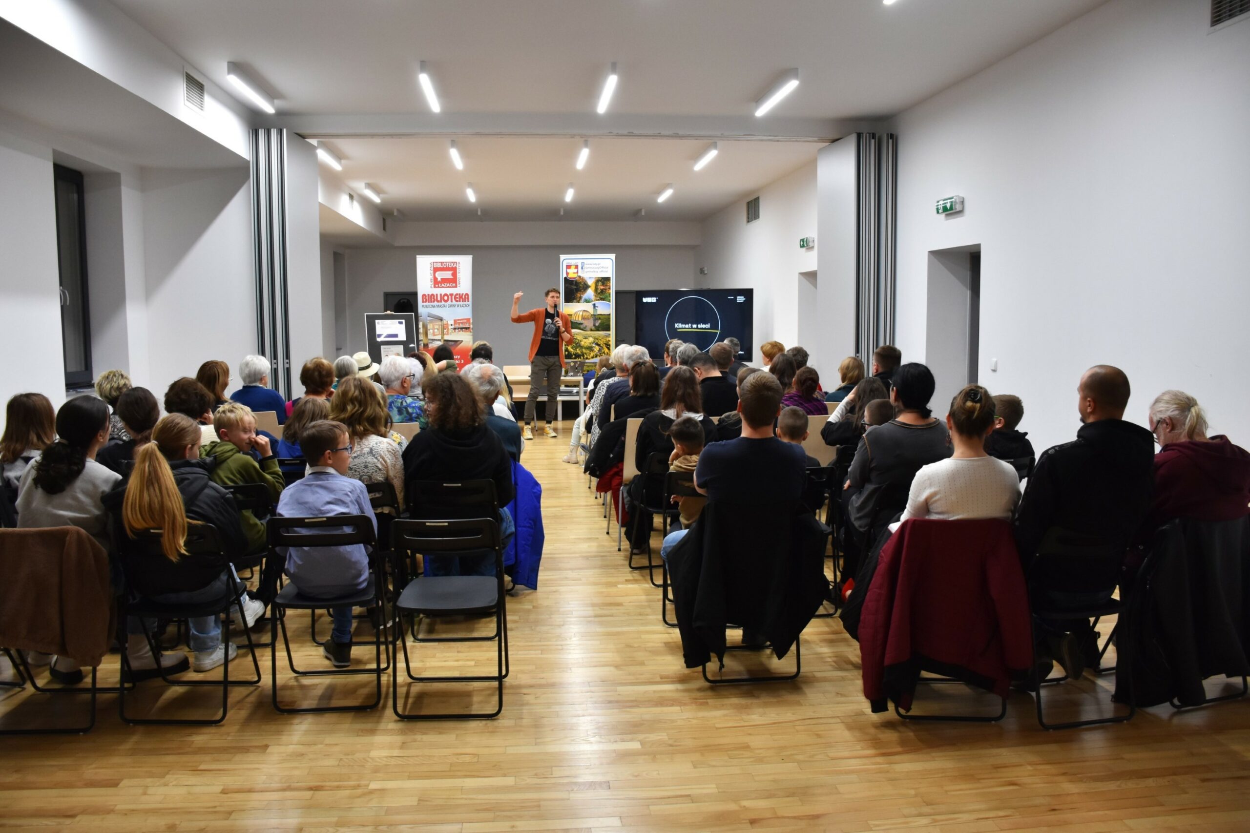 Widownia spotkania klimat w sieci siedząca na krzesłach - zdjęcie zrobione z tyłu, w przedzie prelegent