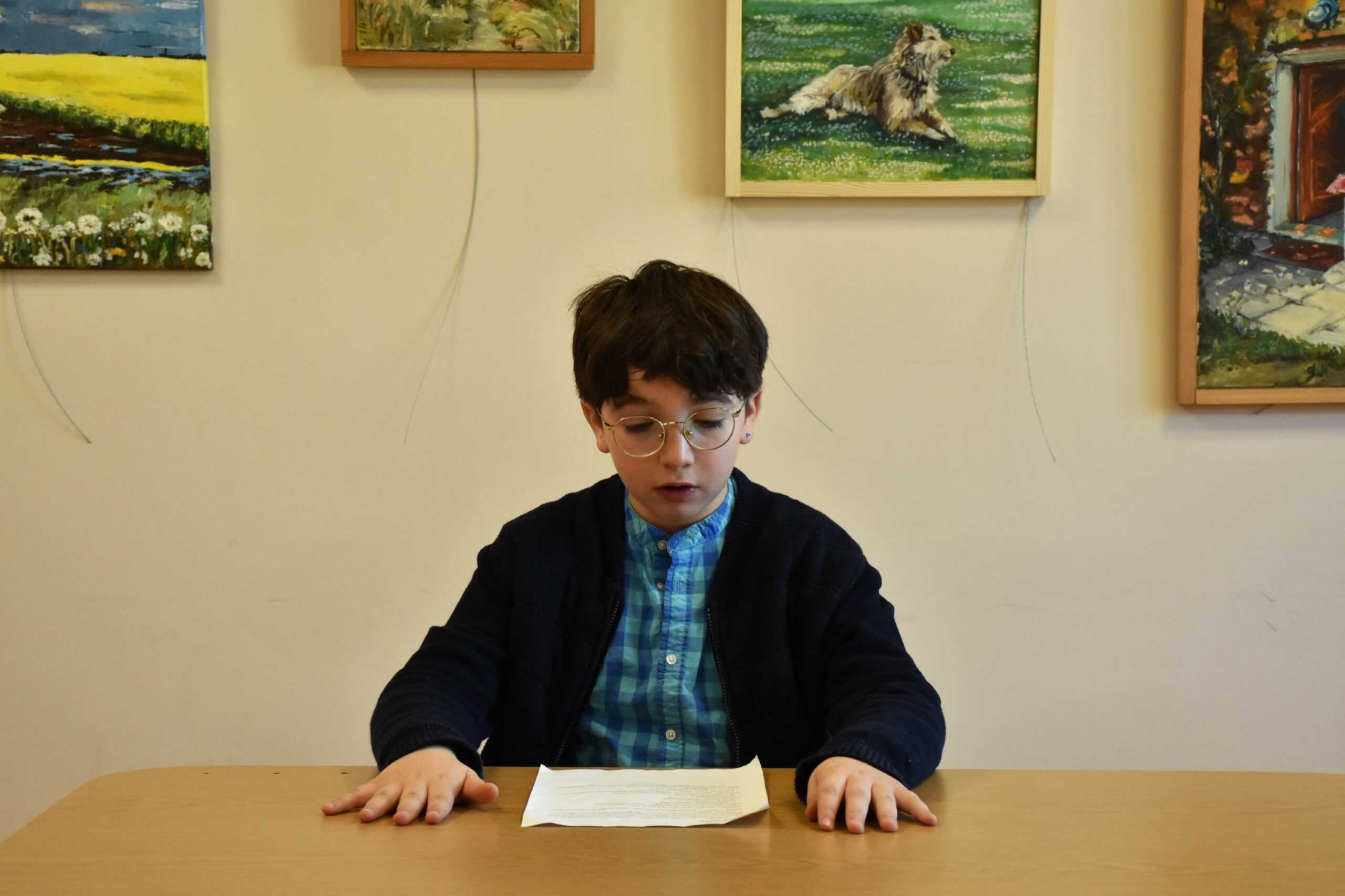 Michał czytający przygotowany tekst siedząc przy stole