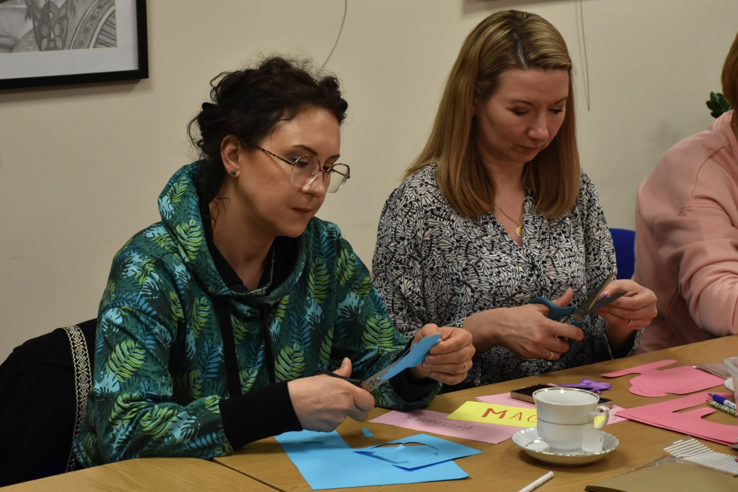 Dwie uczestniczki warsztatu stres pod kontrolą wycinające kształt filiżanki z papieru