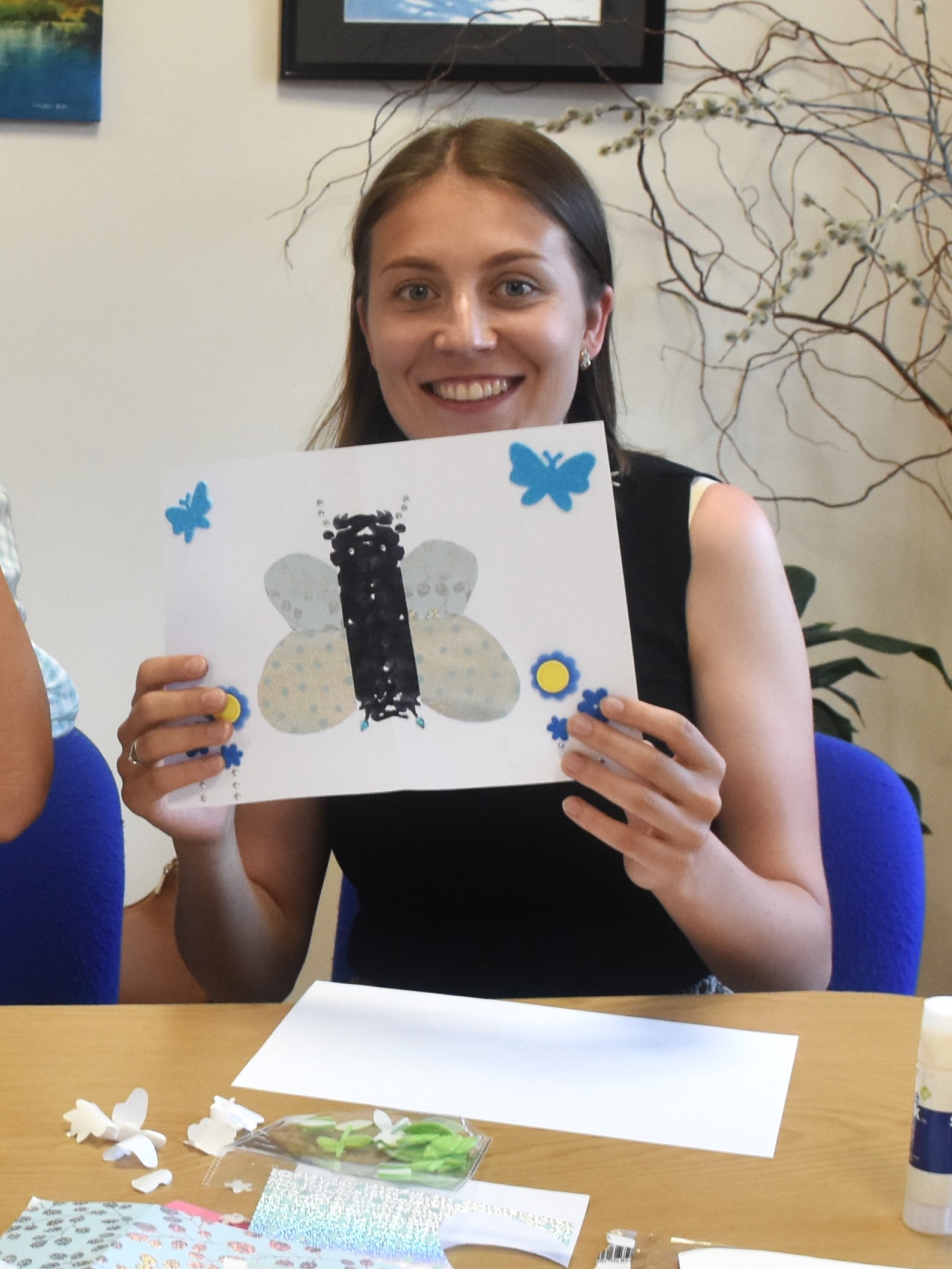 Młoda kobieta, uczestniczka warsztatu oswoić lęk prezentuje z uśmiechem na twarzy swój kleks obrazujących strach