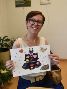 Uczestniczka warsztatu oswoić lęk prezentująca ozdobiony cekinami kleks atramentu symbolizujący strach