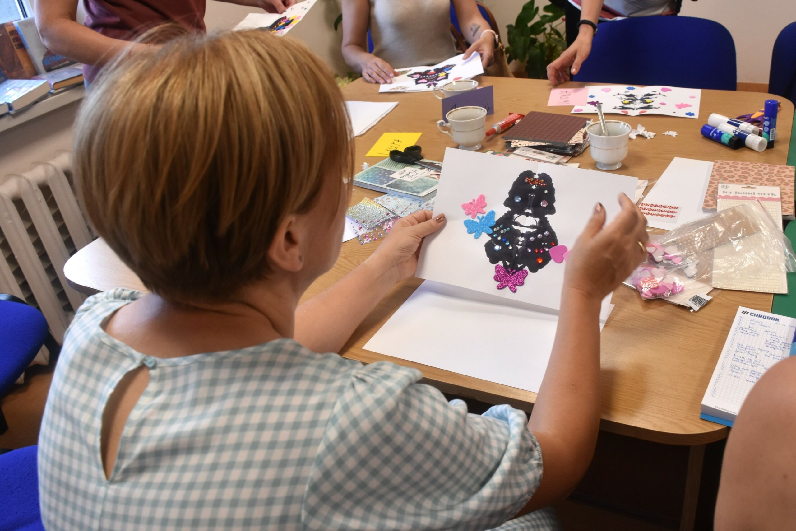 Widok z tyłu na kobietę wpatrującą się w kleks atramentu zrobiony na białej kartce