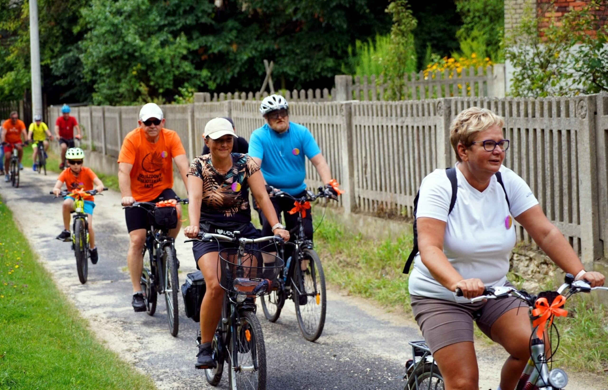 Ośmiu rowerzystów uczestników rajdu odjazdowy bibliotekarz 2025 jadących na rowerach, w tle płot i las