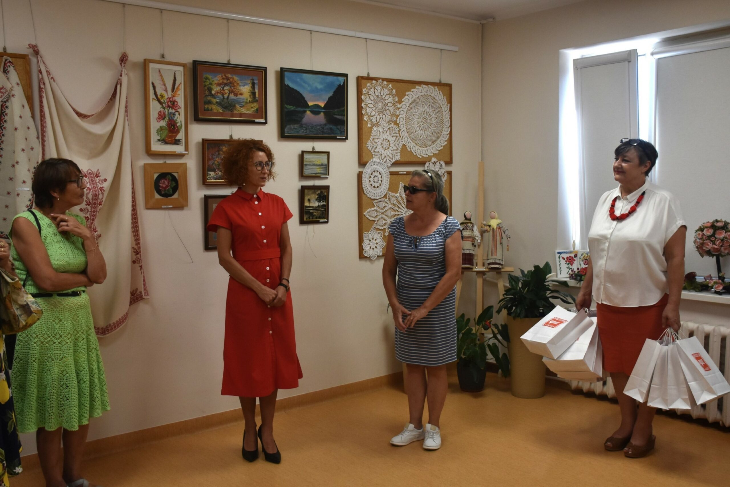 Dyrektor biblioteki przemawia do gości, na zdjęciu jeszcze 3 kobiety, w tle prace klubu kreatywnych kobiet