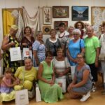 Siedemnaście kobiet na tle serwet rozwieszonych na ścianie - zdjęcie grupowe