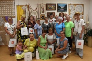 Siedemnaście kobiet na tle serwet rozwieszonych na ścianie - zdjęcie grupowe