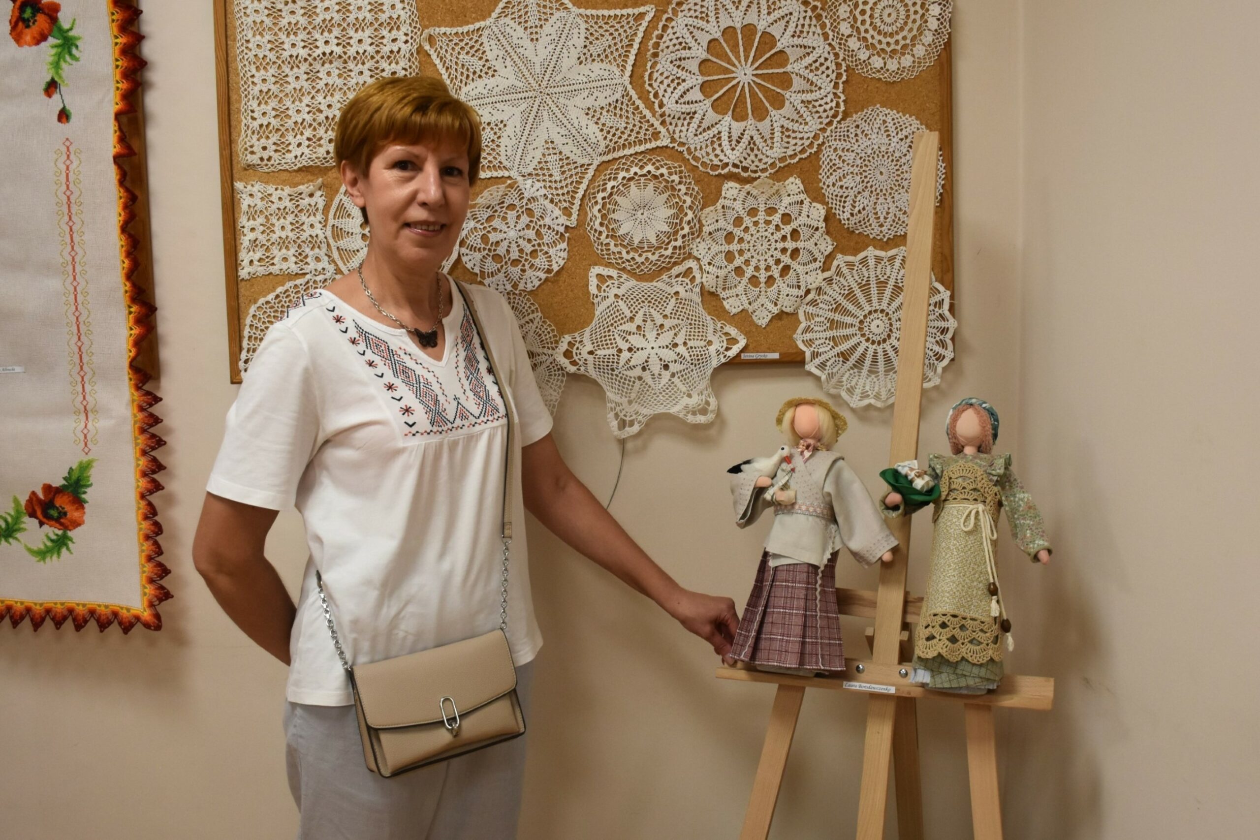 Uczestniczka klubu kreatywnych kobiet pokazująca ręką lalkę szczęścia - rękodzieło