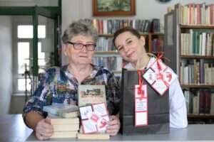 Czytelniczka, bibliotekarka, stos książek i czarna papierowa torba z logiem akcji literacki Zestaw ratunkowy - Zdjęcie portretowe