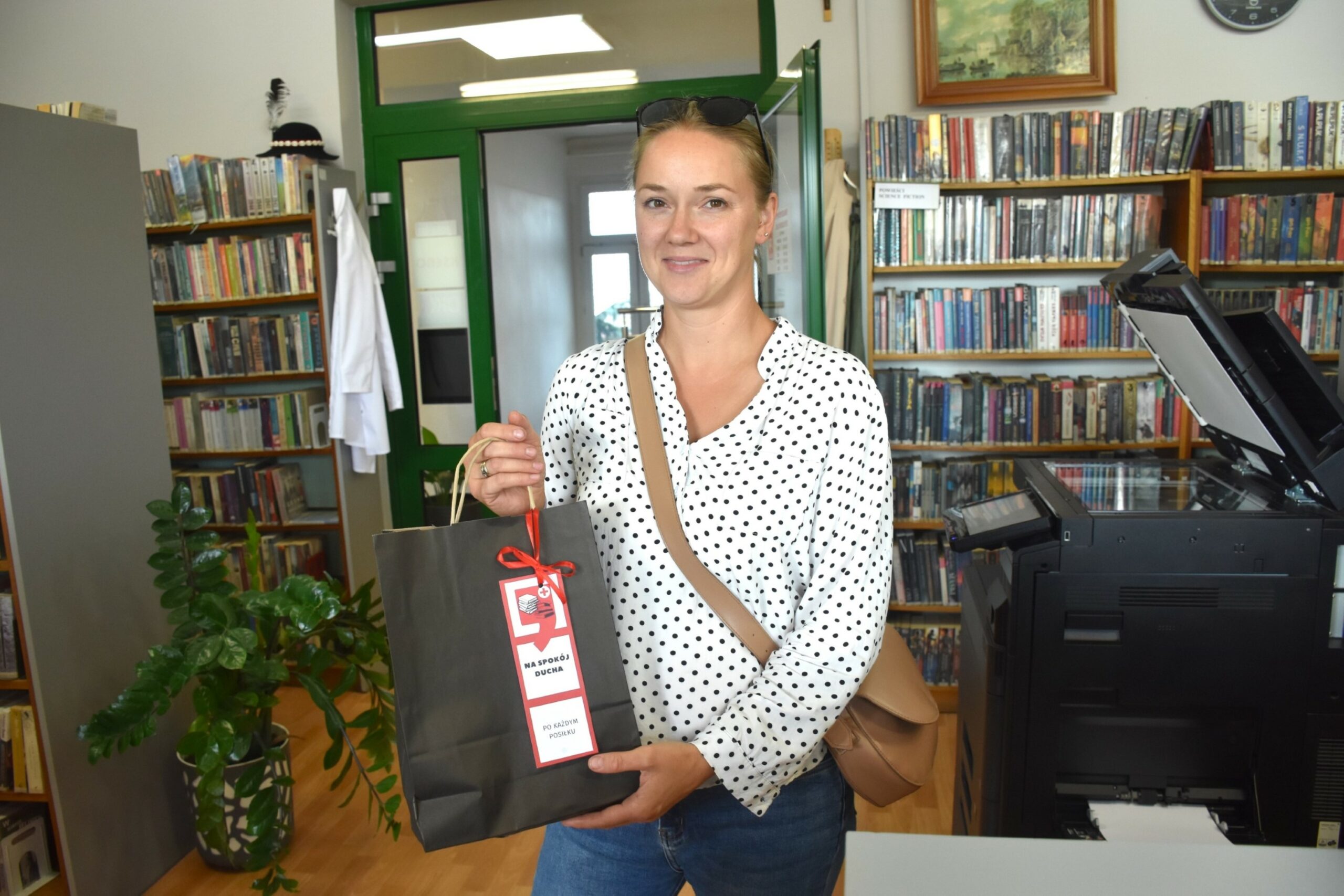 Czytelniczka prezentująca papierową czarną torbę z zakładką akcji literacki zestaw ratunkowy