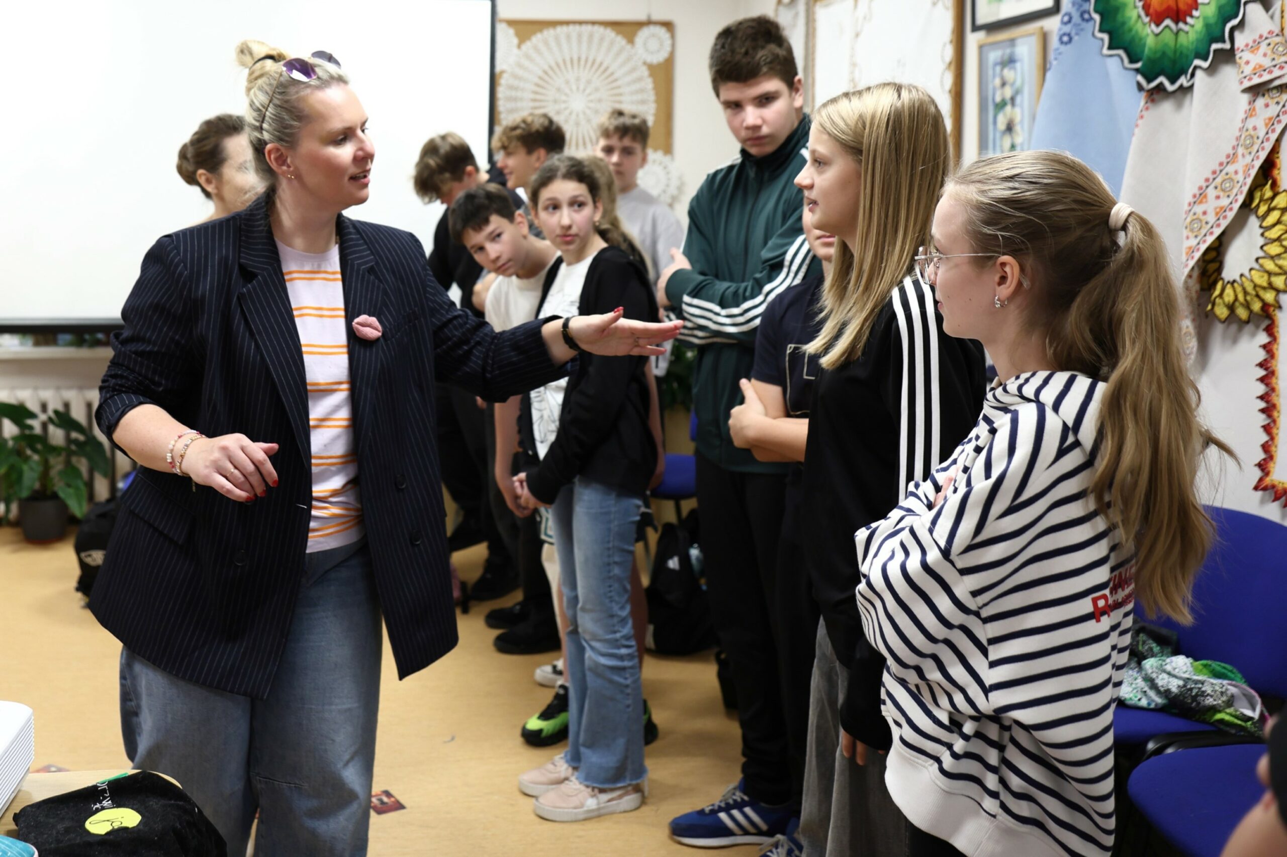 Grupa nastolatków w rozmowie z kobietą prowadzącą warsztat odstresowani