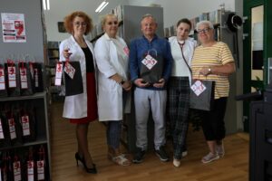 Zdjęcie grupowe - trzy bibliotekarki w lekarskich fartuchach i małżeństwo z torbami pełnymi książek w akcji literacki zestaw ratunkowy na tle regałów z książkami