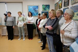 Uczestniczki wernisażu wystawy sztuka dnia codziennego stojące w półkolu, w tle obrazy autorki