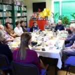 14 członkiń Dyskusyjnego Klubu Książki siedzących wokół stołu