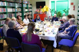 14 członkiń Dyskusyjnego Klubu Książki siedzących wokół stołu