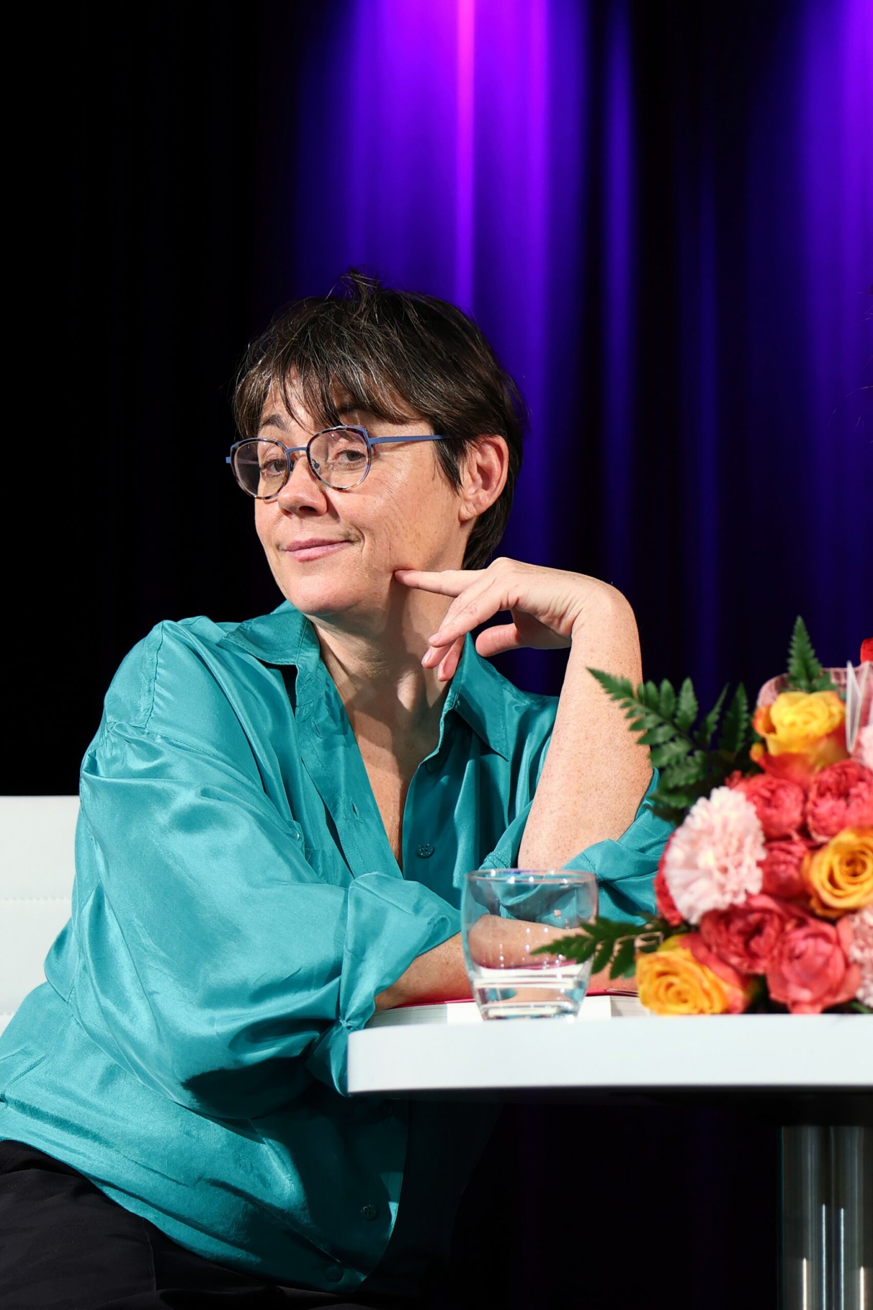 Autorka oparta łokciem o stolik, pozująca do zdjęcia z zawiadiackim spojrzeniem