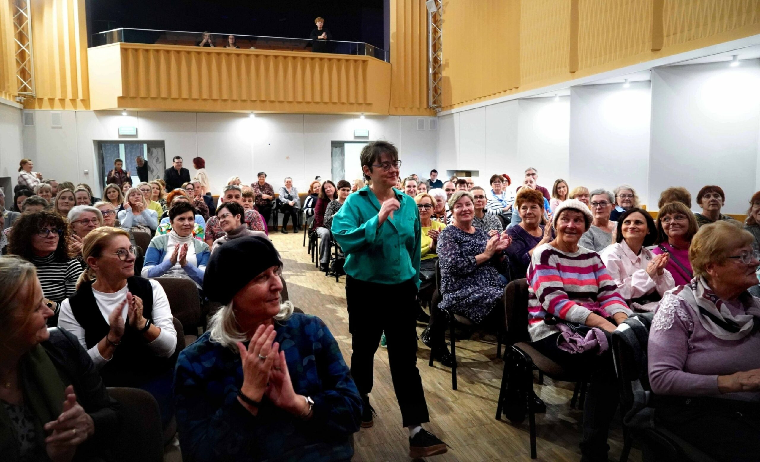 Autorka idąca przez salę pełną siedzących ludzi fotografia Jerzy Kleszcz