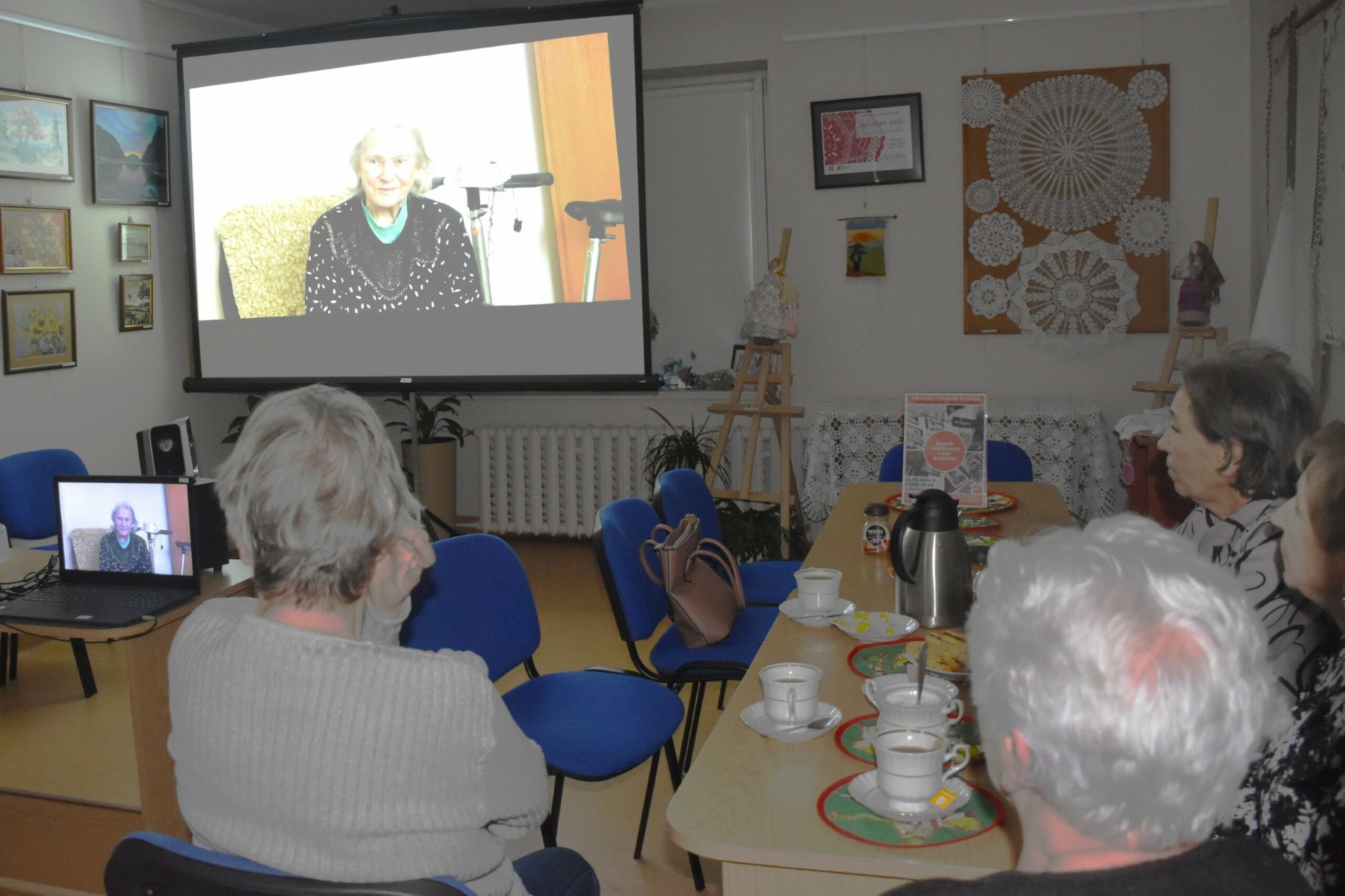 Osoby zgromadzone na spotkaniu Znane i nieznane losy bliskich, siedzące tyłem do fotografa, wpatrzone w ekran rzutnika