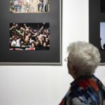 Seniorka tyłem, przyglądająca się fotografii kibiców