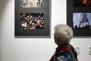 Seniorka tyłem, przyglądająca się fotografii kibiców