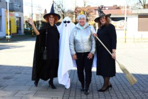 Trzy bibliotekarki w strojach czarownic i ducha z czytelniczką w przestrzeni miasta