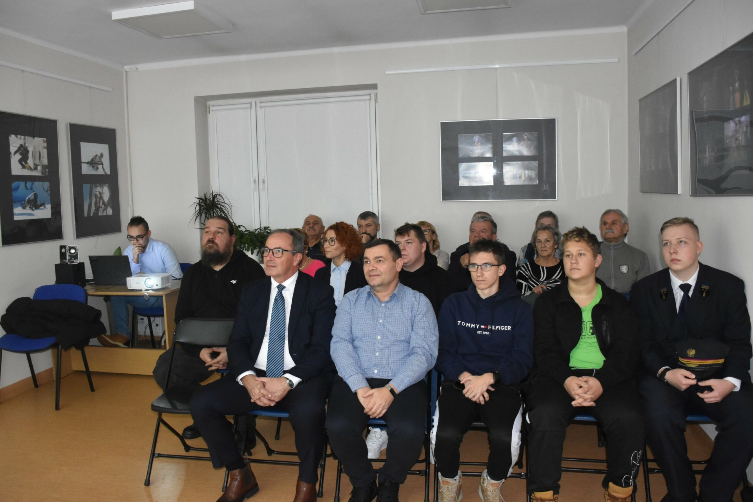 Widok uczestników spotkania Kolej i kolejarze siedzących na krzesłach wpatrujących się w ekran rzutnika