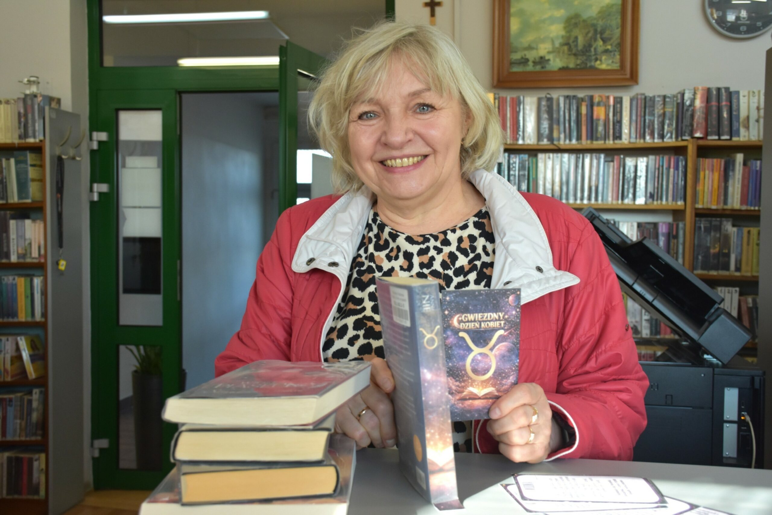 Uśmiechnięta kobieta - uczestniczka akcji Gwiezdny dzień kobiet, na pierwszym planie stos książek