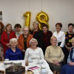 Zdjęcie grupowe - piętnaście klubowiczek klubu książki na tle złotego balona - numeru 18