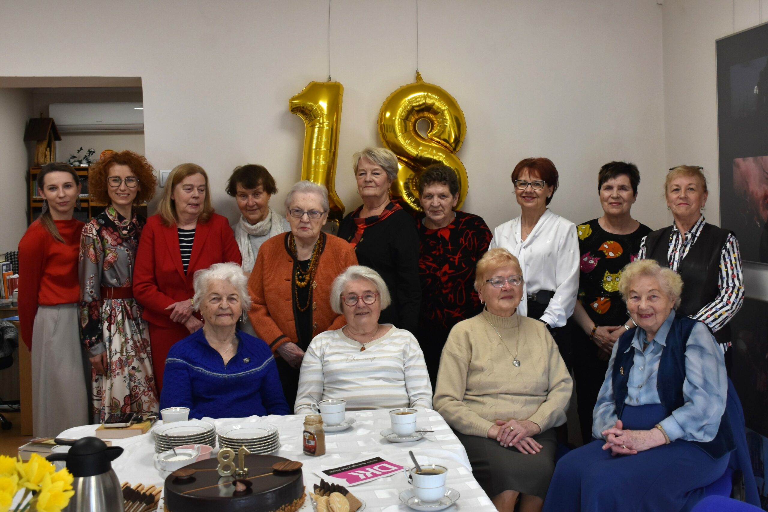 Zdjęcie grupowe - piętnaście klubowiczek klubu książki na tle złotego balona - numeru 18