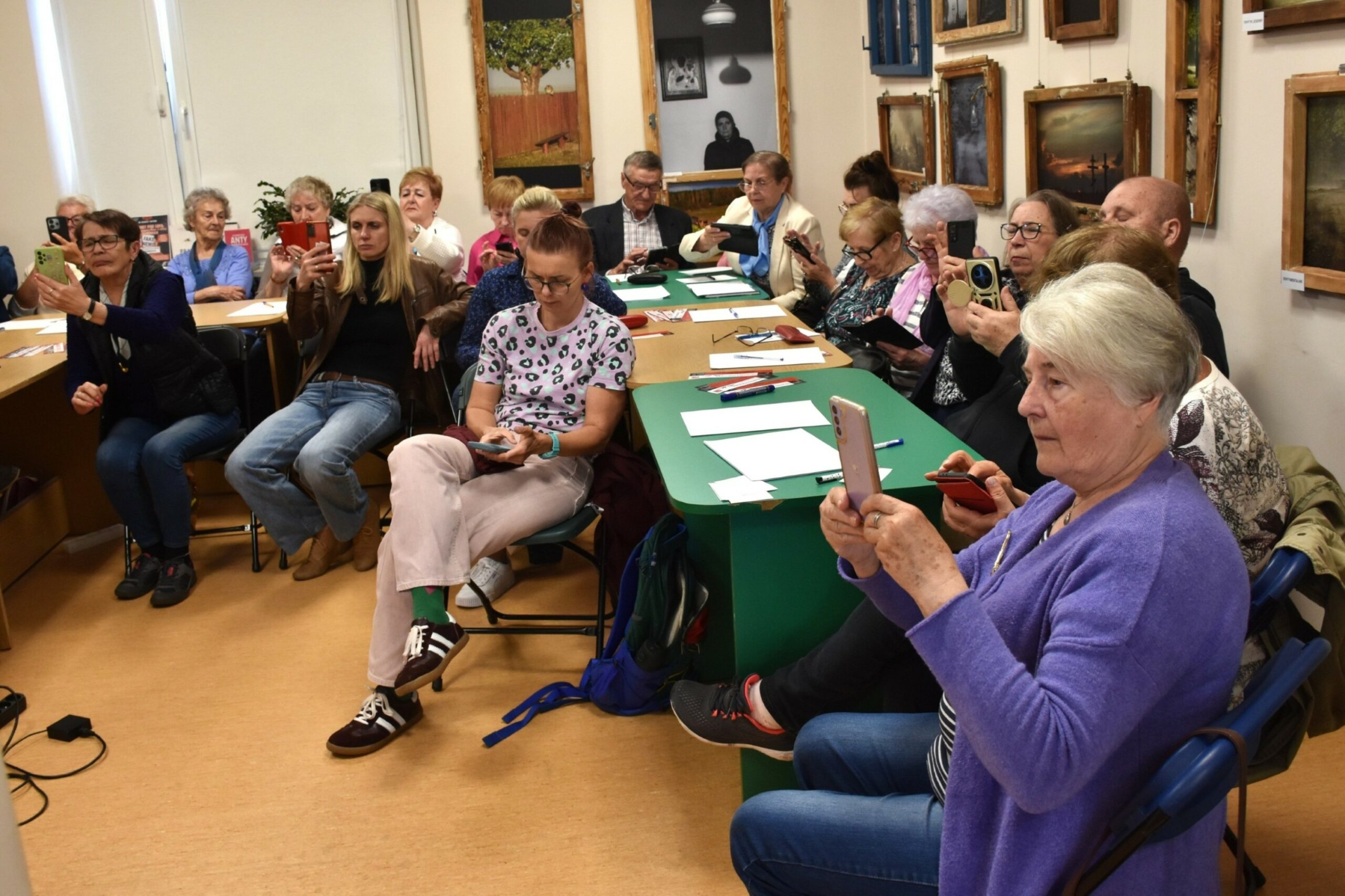 Osiemnastu uczestników warsztatu Internet pod lupą na siedząco, przy zielonym stole