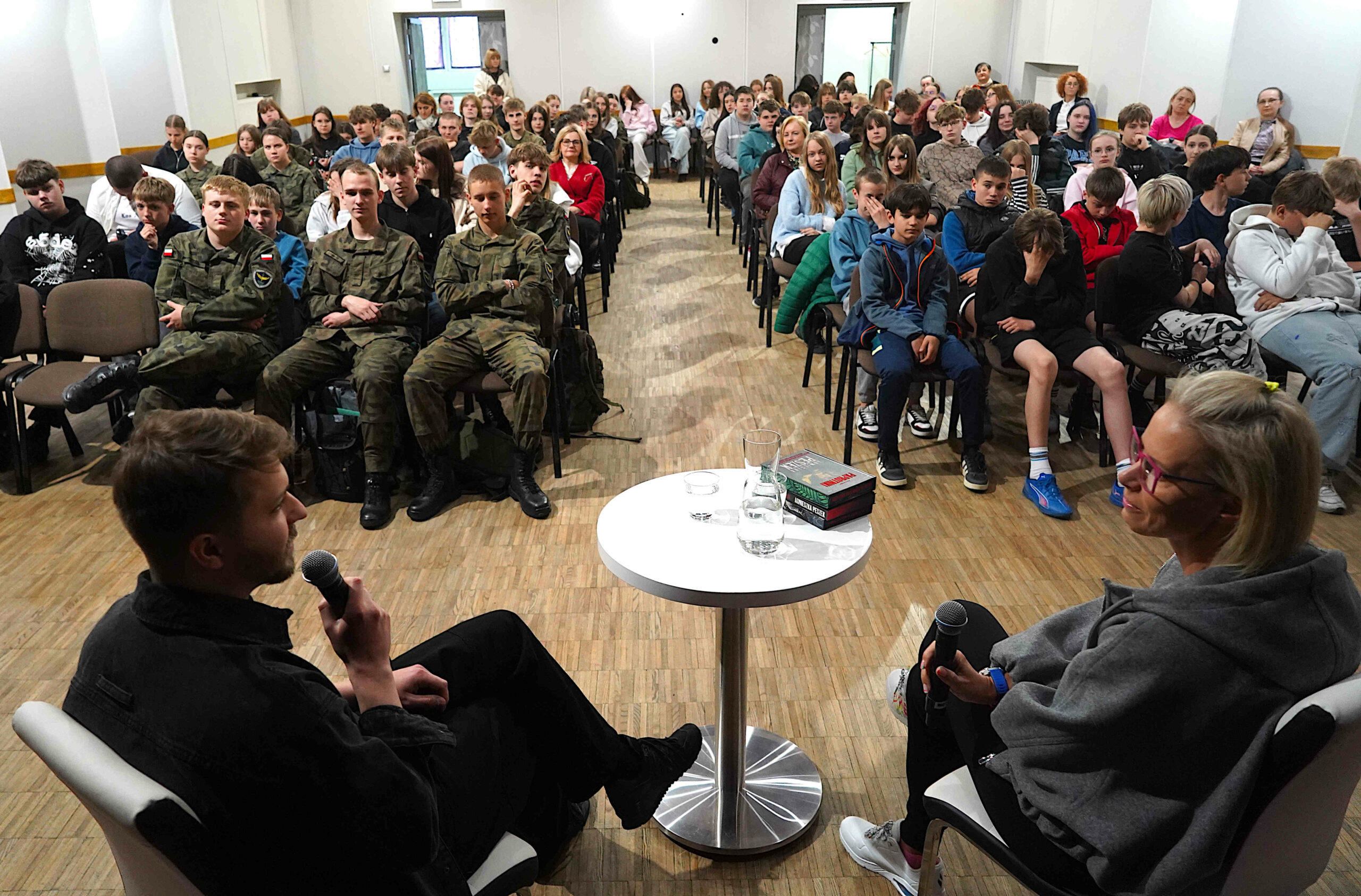 Widok na salę miejskiego ośrodka kultury, wypełnionego młodzieżą oczekującą na spotkanie autorskie
