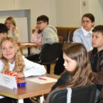 Na pierwszym planie dwie nastolatki i nastolatek - uczestnicy turnieju wiedzy o książce
