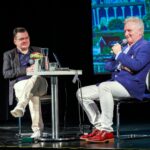 Autor i dziennikarz prowadzący spotkanie Granice świata siedzący przy stoliku na scenie miejskiego ośrodka kultury
