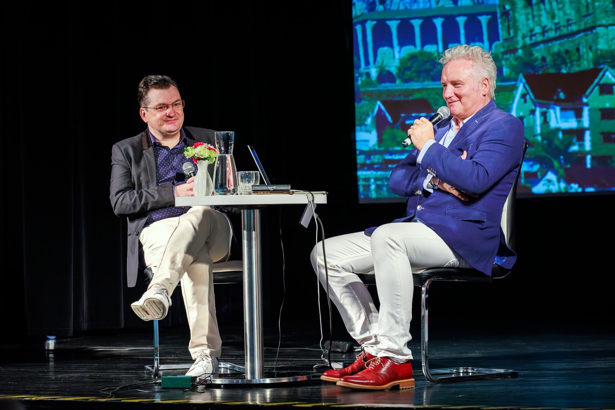 Autor i dziennikarz prowadzący spotkanie Granice świata siedzący przy stoliku na scenie miejskiego ośrodka kultury